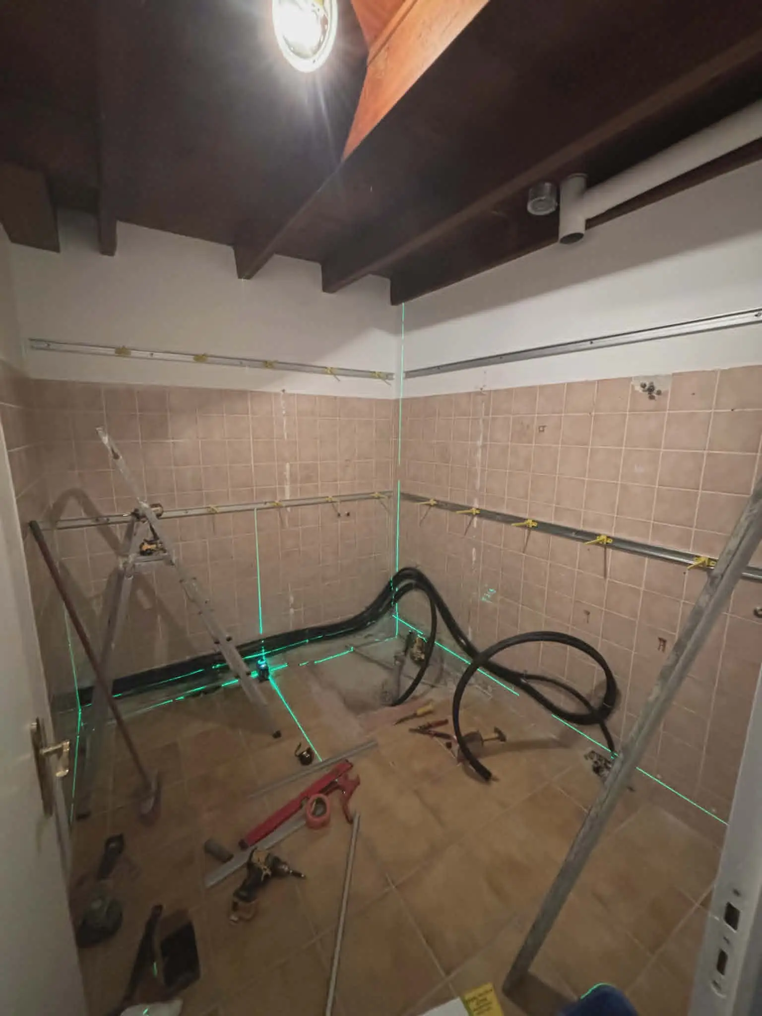 Chantier d'installation chauffage avec niveau laser vert et tuyauterie plancher