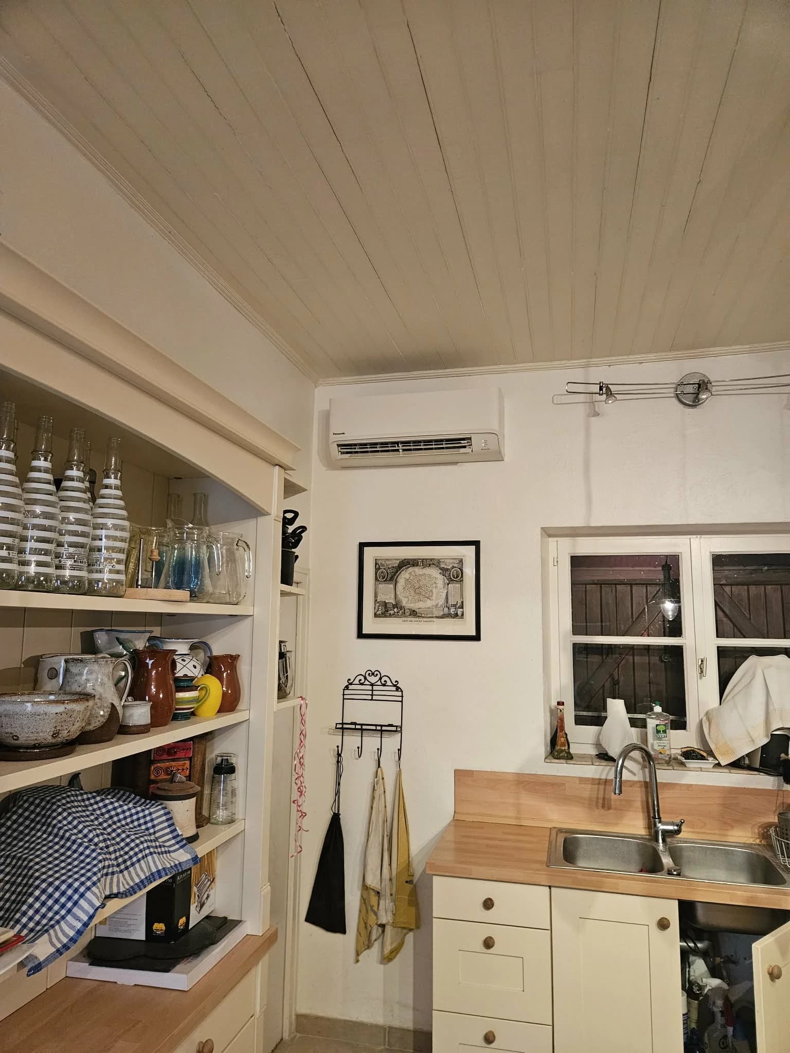 Unité intérieure de climatisation dans une cuisine rustique avec plafond boisé